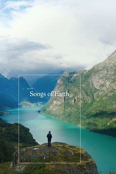 a person standing on top of a mountain next to a lake with mountains in the background