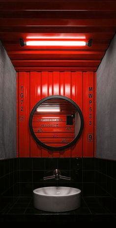 a bathroom with a round mirror on the wall next to a black counter and white sink