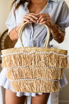 Beachy bliss in a bag! This woven straw tote with playful fringe is your sunny sidekick. Pearls add a touch of elegance, while the magnetic snap keeps essentials safe. Toss in your swimsuit, sunnies, and a good book for the ultimate summer adventure. Item Type: Tote Material: Straw Closure: Magnetic Snap Exterior Details: Woven Straw with straw fringe all-over, Pearl Accents, Top Handle, Gold Hardware Interior Details: Fabric Lined, 1 Slip Pocket 17.7” L x 6.7” W x 12.2” H Straw Tote Bag, Exterior Details, Straw Tote, Summer Adventures, A Bag, Interior Details, Gold Hardware, Top Handle, Sale Items