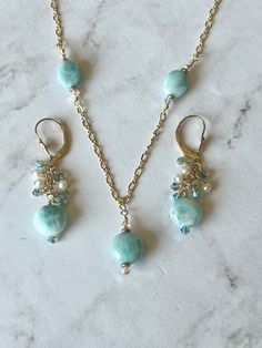 This set has a genuine larimar necklace and earring set.  The necklace is on a gold filled dainty figure & chain. The round stone is 10 mm with the ovals measuring also 10mm.  The necklace is 24 inches with a gold filled lobster clasp.  The earrings also have 10 mm round larimar stones on gold filled lever wires.  They have 3 mm freshwater pearls and Swarovski bicones. Elegant Amazonite Jewelry Gift, Elegant Amazonite Jewelry For Gifts, Elegant Amazonite Dangle Jewelry, Oval Amazonite Jewelry As Gift, Oval Amazonite Jewelry Gift, Oval Amazonite Jewelry For Gift, Adjustable Larimar Jewelry For Anniversary, Hypoallergenic Amazonite Jewelry As Gift, Elegant Larimar Dangle Earrings