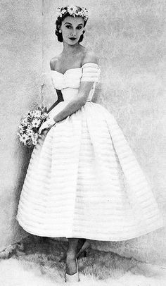 a black and white photo of a woman in a dress with flowers on her head