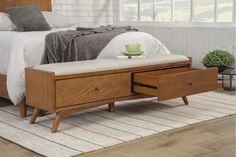 a bed sitting on top of a white rug next to a wooden table with drawers