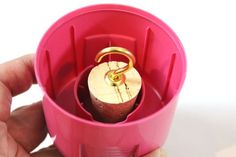 a person holding a pink cup with a gold ring in it