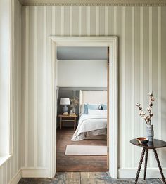 an open door leading to a bedroom with striped walls and wood flooring on the other side