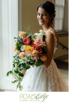 a woman in a wedding dress holding a bouquet of flowers and smiling at the camera