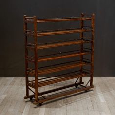 an old wooden rack with several shelves on it's sides, sitting on a hard wood floor