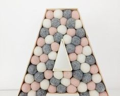 a letter made out of rocks with a white triangle in the middle and pink and grey balls at the bottom