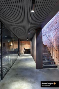 an empty hallway with brick walls and metal railings leading up to the second floor