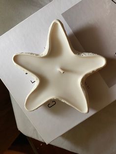 a white ceramic starfish dish sitting on top of a piece of paper next to an envelope