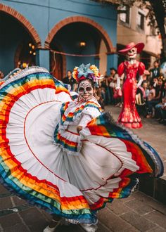 two people in colorful costumes are dancing on the street