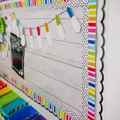 a colorful bulletin board with paper clips hanging from it's sides and colored pencils on the pegs