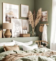 a bedroom with green walls and pictures on the wall above the bed, along with a wicker basket filled with dried grass