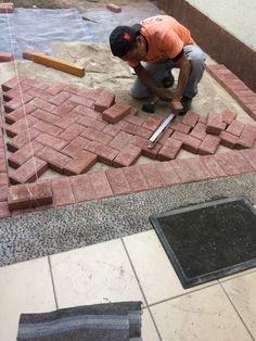 a man laying bricks on top of a floor next to a hole in the ground