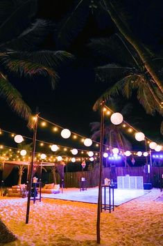 an outdoor event with lights strung from the ceiling and palm trees in the foreground