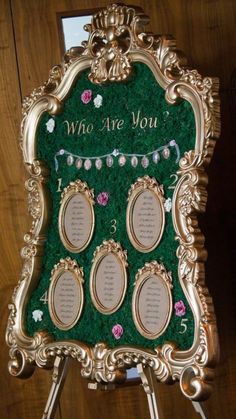 a green and gold wedding seating chart with flowers on the front, which reads who are you?