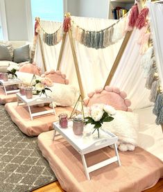 a living room filled with lots of furniture and flowers on top of tables in front of a window