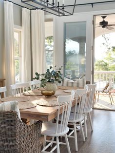 the dining room table is set with white chairs and placemats, along with wicker baskets