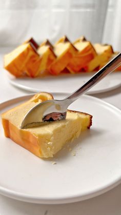 a piece of cake on a white plate with a fork in it and some other desserts behind it