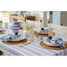 a blue and white table setting with plates, vases and flowers on the table