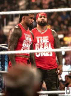 two men standing next to each other in front of a crowd at a wrestling match