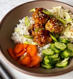 a bowl filled with rice, meatballs and veggies next to chopsticks