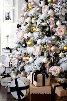 a christmas tree decorated with pink and gold ornaments, black and white presents under the tree