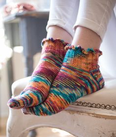 a woman's feet in colorful socks on top of a white chair with chains