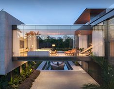 an exterior view of a modern house with pool in the foreground and outdoor furniture on the other side