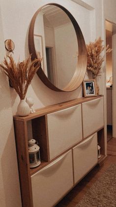 a large round mirror sitting on top of a wooden shelf next to a white dresser