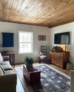 a living room filled with furniture and a flat screen tv on top of a wooden ceiling