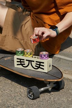 a man sitting on the ground with his skateboard and cans of beer in front of him