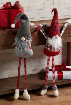 two gnomes standing next to each other with presents on the shelf in front of them