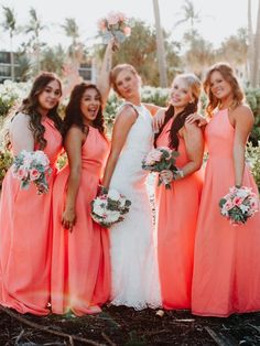 a group of women standing next to each other wearing dresses and holding bouquets in their hands