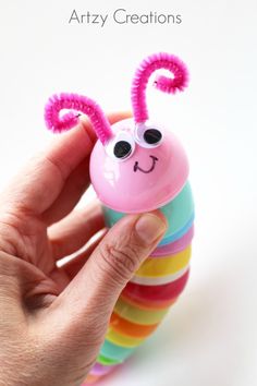 a hand holding a toy with a pink caterpillar on it