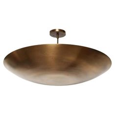 a large brass bowl hanging from the ceiling with a light on it's side