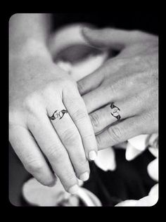 two people holding hands with tattoos on their fingers