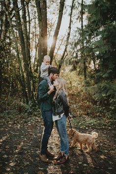 a man, woman and child are standing in the woods with their dog on a leash