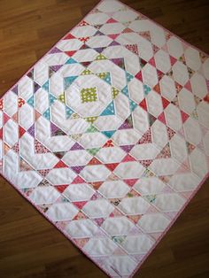 a quilted table topper on a wooden floor with a pattern in the middle