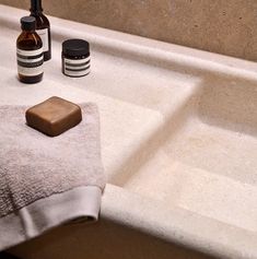 a bathroom sink with soap and lotion on it next to a towel, bottle of deodorant