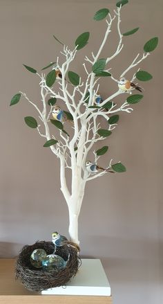 a white tree with birds sitting on it's branches in front of a nest