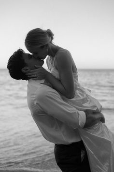 a bride and groom kissing on the beach