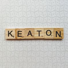 the word keaton spelled with scrabble letters on a white wallpapered surface