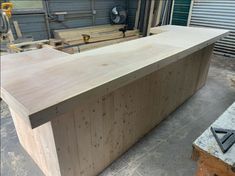 a large wooden counter sitting in the middle of a room next to other woodworking tools