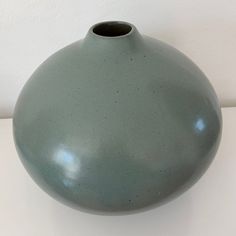 a green vase sitting on top of a white table