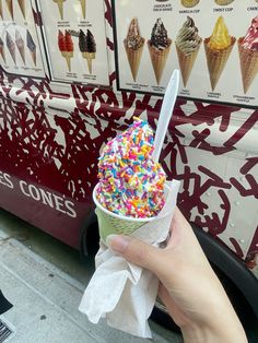 a hand holding an ice cream cone with sprinkles