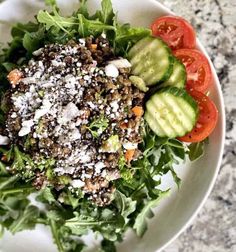 a salad with tomatoes, cucumbers and feta cheese is on a white plate