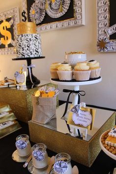 a table topped with cupcakes and cakes next to framed pictures on the wall