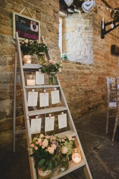 a ladder decorated with flowers and notes for guests to write on the wall next to them