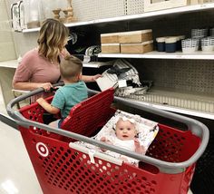 a woman pushing a shopping cart with a baby in it