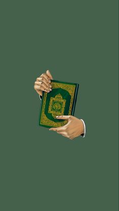 two hands holding an open book in front of a green background